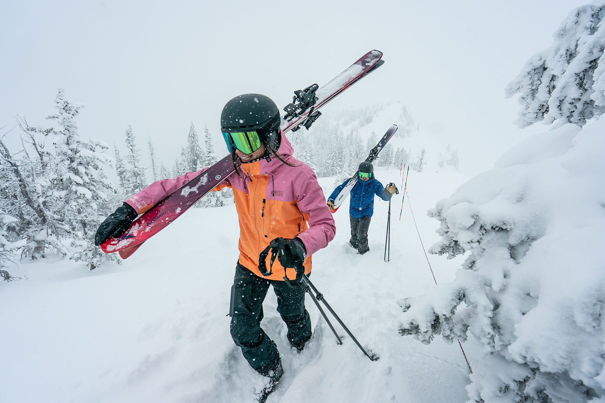 Zwei Skifahrer tragen ihre Ski durch den Tiefschnee